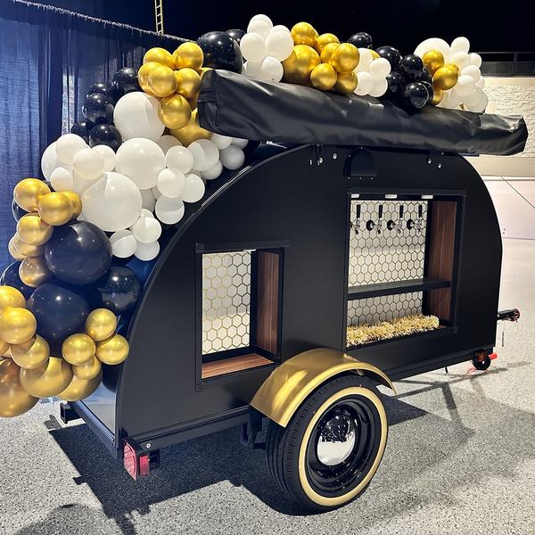 Tap trailer decorated with a black, white and gold balloon garland for a party